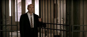 Movie still from “The Chorus” (2004), directed by Christophe Barratier – A man in a suit standing in front of a jail cell; Medium shot, Low angle