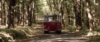 Movie still from “The Chorus” (2004), directed by Christophe Barratier – A red bus driving down a dirt road through the woods; Extreme Wide shot, Low angle