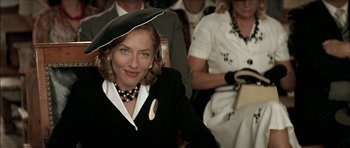 Movie still from “The Chorus” (2004), directed by Christophe Barratier – A woman wearing a black hat and a black suit; Close Up shot, Over the shoulder angle
