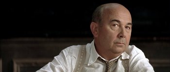 Movie still from “The Chorus” (2004), directed by Christophe Barratier – An older man wearing a neck tie looking off into the distance; Close Up shot, Low angle