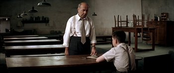 Movie still from “The Chorus” (2004), directed by Christophe Barratier – An older man and a young boy in a classroom setting; Medium shot, Over the shoulder angle