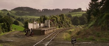 Movie still from “The Chronicles of Narnia: The Lion, the Witch and the Wardrobe” (2005), directed by Andrew Adamson – Two people are standing on a train track near a train station; Extreme Wide shot, High angle