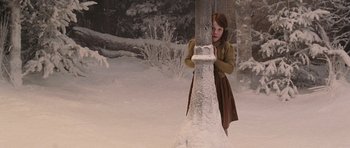 Movie still from “The Chronicles of Narnia: The Lion, the Witch and the Wardrobe” (2005), directed by Andrew Adamson – A young girl standing next to a tree in the middle of a snowy forest; Medium shot, High angle