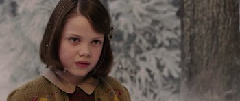 Movie still from “The Chronicles of Narnia: The Lion, the Witch and the Wardrobe” (2005), directed by Andrew Adamson – A young girl is standing in front of a snowy background; Close Up shot, Over the shoulder angle