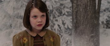 Movie still from “The Chronicles of Narnia: The Lion, the Witch and the Wardrobe” (2005), directed by Andrew Adamson – A young girl is standing in front of a snowy tree; Close Up shot, Over the shoulder angle