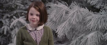 Movie still from “The Chronicles of Narnia: The Lion, the Witch and the Wardrobe” (2005), directed by Andrew Adamson – A little girl in a green sweater standing in front of a tree; Close Up shot, Over the shoulder angle