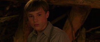 Movie still from “The Chronicles of Narnia: The Lion, the Witch and the Wardrobe” (2005), directed by Andrew Adamson – A young man in a gray shirt and suspenders looks into the camera; Close Up shot, Low angle