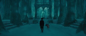 Movie still from “The Chronicles of Narnia: The Lion, the Witch and the Wardrobe” (2005), directed by Andrew Adamson – A man and a dog are walking through a dark forest; Wide shot, High angle