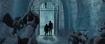 Movie still from “The Chronicles of Narnia: The Lion, the Witch and the Wardrobe” (2005), directed by Andrew Adamson – Two people are standing in the snow near a gate; Wide shot, High angle