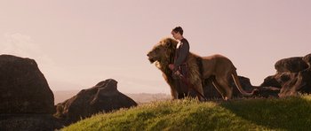 Movie still from “The Chronicles of Narnia: The Lion, the Witch and the Wardrobe” (2005), directed by Andrew Adamson – A man standing on top of a hill next to a lion; Wide shot, Low angle