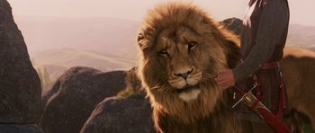 Movie still from “The Chronicles of Narnia: The Lion, the Witch and the Wardrobe” (2005), directed by Andrew Adamson – A person petting a lion's head; Close Up shot, Low angle