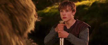 Movie still from “The Chronicles of Narnia: The Lion, the Witch and the Wardrobe” (2005), directed by Andrew Adamson – A young man holding a sword in his hand; Close Up shot, Low angle
