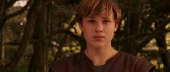 Movie still from “The Chronicles of Narnia: The Lion, the Witch and the Wardrobe” (2005), directed by Andrew Adamson – A young man in a brown shirt is standing in front of a tree; Close Up shot, Low angle