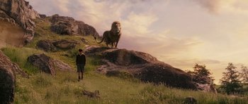 Movie still from “The Chronicles of Narnia: The Lion, the Witch and the Wardrobe” (2005), directed by Andrew Adamson – A man standing on top of a hill next to a lion; Wide shot, Low angle