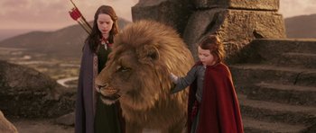 Movie still from “The Chronicles of Narnia: The Lion, the Witch and the Wardrobe” (2005), directed by Andrew Adamson – Two young girls standing next to a large lion; Medium shot, Low angle