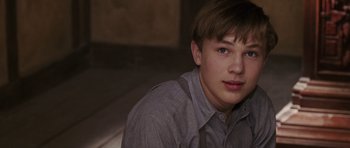 Movie still from “The Chronicles of Narnia: The Lion, the Witch and the Wardrobe” (2005), directed by Andrew Adamson – A young man in a gray shirt is looking at the camera; Close Up shot, Over the shoulder angle