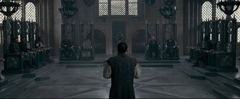 Movie still from “The Chronicles of Narnia: Prince Caspian” (2008), directed by Andrew Adamson – A man standing in front of a group of people in a room; Wide shot, High angle