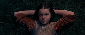 Movie still from “The Chronicles of Narnia: Prince Caspian” (2008), directed by Andrew Adamson – A young girl laying in the grass with her hands behind her head; Close Up shot, High angle