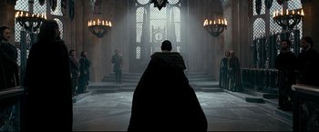 Movie still from “The Chronicles of Narnia: Prince Caspian” (2008), directed by Andrew Adamson – A man wearing a black cape standing in front of a window; Wide shot, Low angle