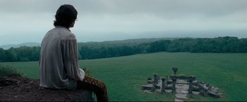 Movie still from “The Chronicles of Narnia: Prince Caspian” (2008), directed by Andrew Adamson – A man sitting on top of a hill next to a field; Extreme Wide shot, Low angle