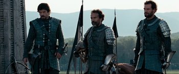 Movie still from “The Chronicles of Narnia: Prince Caspian” (2008), directed by Andrew Adamson – A man in armor standing in front of a flag; Medium shot, Low angle