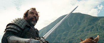 Movie still from “The Chronicles of Narnia: Prince Caspian” (2008), directed by Andrew Adamson – A man with a beard holding a sword in front of a mountain; Medium shot, Low angle