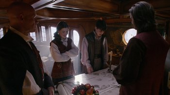 Movie still from “The Chronicles of Narnia: The Voyage of the Dawn Treader” (2010), directed by Michael Apted – A group of people standing around a table; Medium shot, Over the shoulder angle