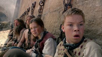Movie still from “The Chronicles of Narnia: The Voyage of the Dawn Treader” (2010), directed by Michael Apted – A group of people sitting next to each other on chains; Close Up shot, Low angle