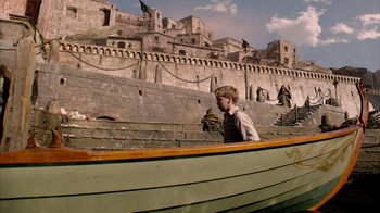 Movie still from “The Chronicles of Narnia: The Voyage of the Dawn Treader” (2010), directed by Michael Apted – A man sitting in a boat in front of a castle; Wide shot, High angle