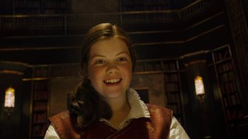 Movie still from “The Chronicles of Narnia: The Voyage of the Dawn Treader” (2010), directed by Michael Apted – A young girl smiling for the camera in a library; Close Up shot, Low angle