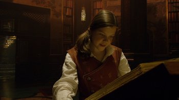Movie still from “The Chronicles of Narnia: The Voyage of the Dawn Treader” (2010), directed by Michael Apted – A young girl is looking at a book in a library; Medium shot, Low angle