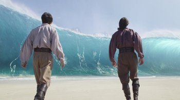 Movie still from “The Chronicles of Narnia: The Voyage of the Dawn Treader” (2010), directed by Michael Apted – Two men are standing on the beach looking at a large wave; Wide shot, Low angle