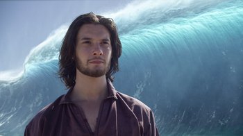 Movie still from “The Chronicles of Narnia: The Voyage of the Dawn Treader” (2010), directed by Michael Apted – A man standing in front of a large wave in the ocean; Close Up shot, Low angle