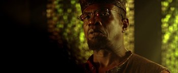 Movie still from “The Chronicles of Riddick” (2004), directed by David Twohy – A person wearing glasses and a crown; Close Up shot, Low angle