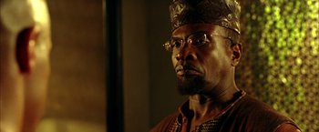 Movie still from “The Chronicles of Riddick” (2004), directed by David Twohy – A person wearing glasses and a crown; Close Up shot, Low angle