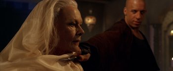 Movie still from “The Chronicles of Riddick” (2004), directed by David Twohy – An older woman is getting her hair cut by a barber; Close Up shot, Over the shoulder angle