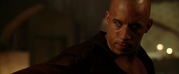 Movie still from “The Chronicles of Riddick” (2004), directed by David Twohy – A bald man is looking into the distance; Close Up shot, Over the shoulder angle