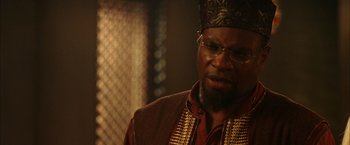 Movie still from “The Chronicles of Riddick” (2004), directed by David Twohy – A man with a beard wearing glasses and wearing a crown; Close Up shot, Over the shoulder angle