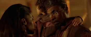 Movie still from “The Chronicles of Riddick” (2004), directed by David Twohy – A person wearing glasses and a hat; Close Up shot, Over the shoulder angle