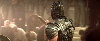 Movie still from “The Chronicles of Riddick” (2004), directed by David Twohy – A man in a metal armor is standing in front of a group of people; Close Up shot, Over the shoulder angle