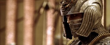 Movie still from “The Chronicles of Riddick” (2004), directed by David Twohy – A person wearing a helmet and holding a cell phone; Close Up shot, Low angle