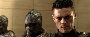 Movie still from “The Chronicles of Riddick” (2004), directed by David Twohy – A man in a helmet and a man in a suit of armor; Close Up shot, Over the shoulder angle