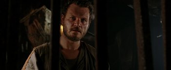 Movie still from “The Chronicles of Riddick” (2004), directed by David Twohy – A person with a beard looking at the camera; Close Up shot, Over the shoulder angle