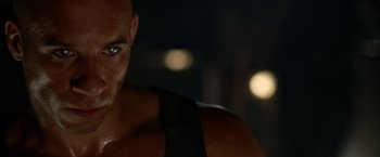 Movie still from “The Chronicles of Riddick” (2004), directed by David Twohy – A man's face in the dark; Close Up shot, Over the shoulder angle