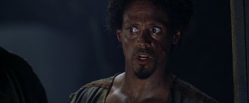 Movie still from “The Chronicles of Riddick” (2004), directed by David Twohy – A person with a face covered in dirt; Close Up shot, Over the shoulder angle