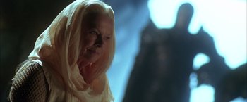 Movie still from “The Chronicles of Riddick” (2004), directed by David Twohy – An older woman wearing a white scarf looking at the camera; Close Up shot, Low angle