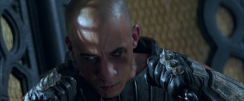 Movie still from “The Chronicles of Riddick” (2004), directed by David Twohy – A man with a bald head wearing armor; Close Up shot, High angle