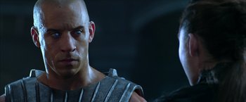 Movie still from “The Chronicles of Riddick” (2004), directed by David Twohy – A bald man with a shaved head wearing armor; Close Up shot, Over the shoulder angle