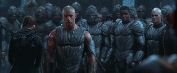 Movie still from “The Chronicles of Riddick” (2004), directed by David Twohy – A group of men in armor standing next to each other in a room; Medium shot, High angle