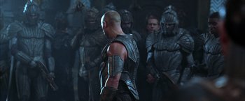 Movie still from “The Chronicles of Riddick” (2004), directed by David Twohy – A group of men in armor standing next to each other in a dark room; Medium shot, Over the shoulder angle
